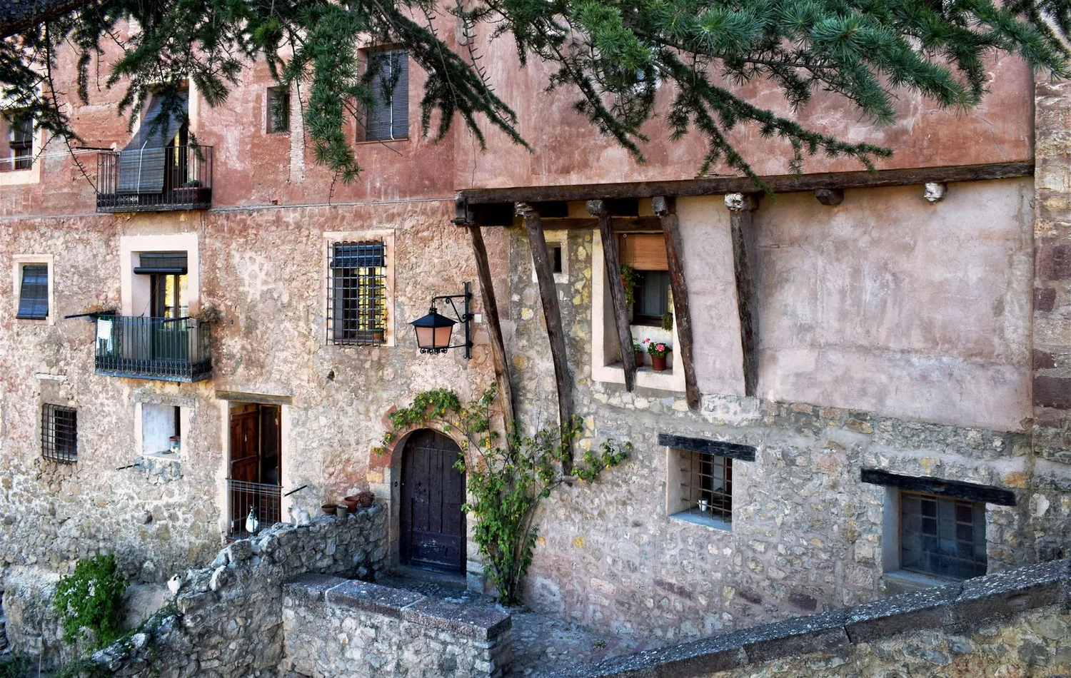 Traditionelles Altstadthaus in Albarracín mit Holzbalken, Steinmauer und rötlichem Putz