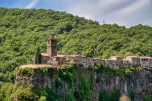 La Garrotxa in Katalonien: Vulkane, Buchenwald und Dörfer entdecken Castellfollit de la Roca auf einer bewaldeten Basaltklippe in La Garrotxa
