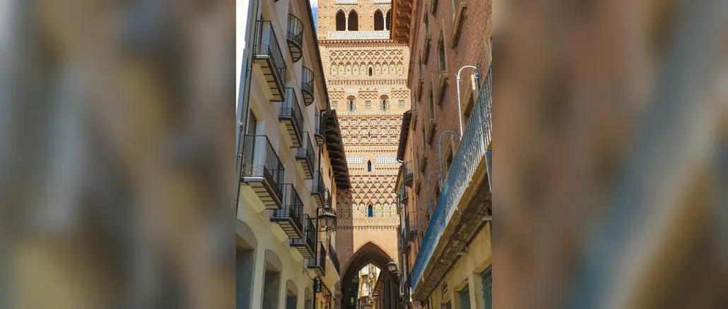 Reich verzierter Mudéjar-Turm über einer schmalen Straße in der Altstadt von Teruel